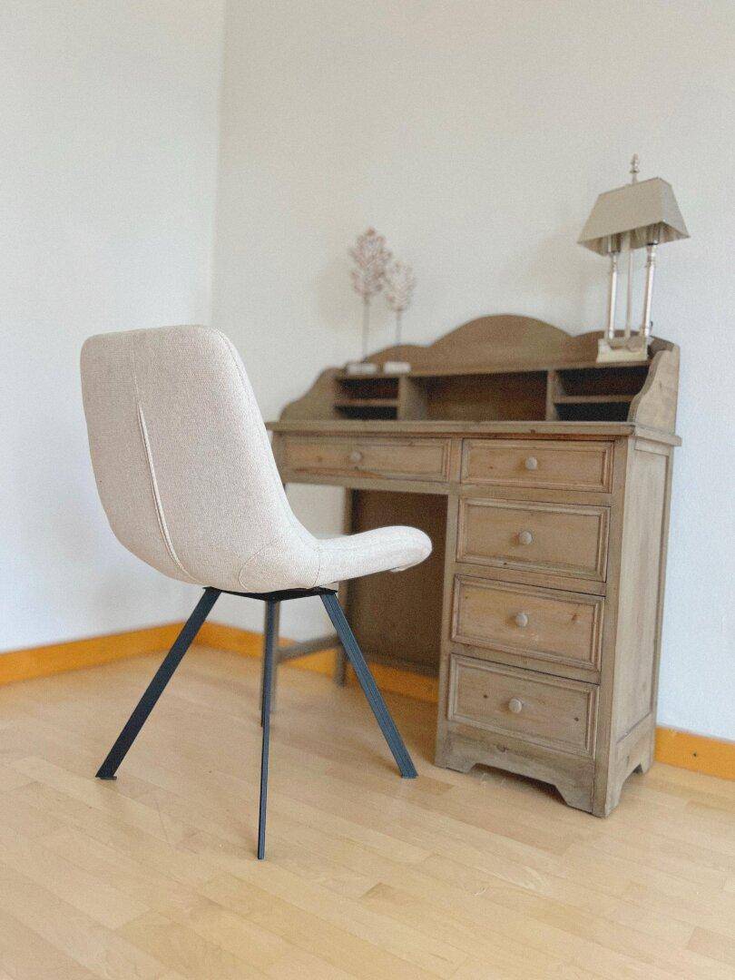 Gemütlicher Arbeitsbereich mit einem klassischen Holzschreibtisch und modernem Stuhl auf hellem Parkettboden.
