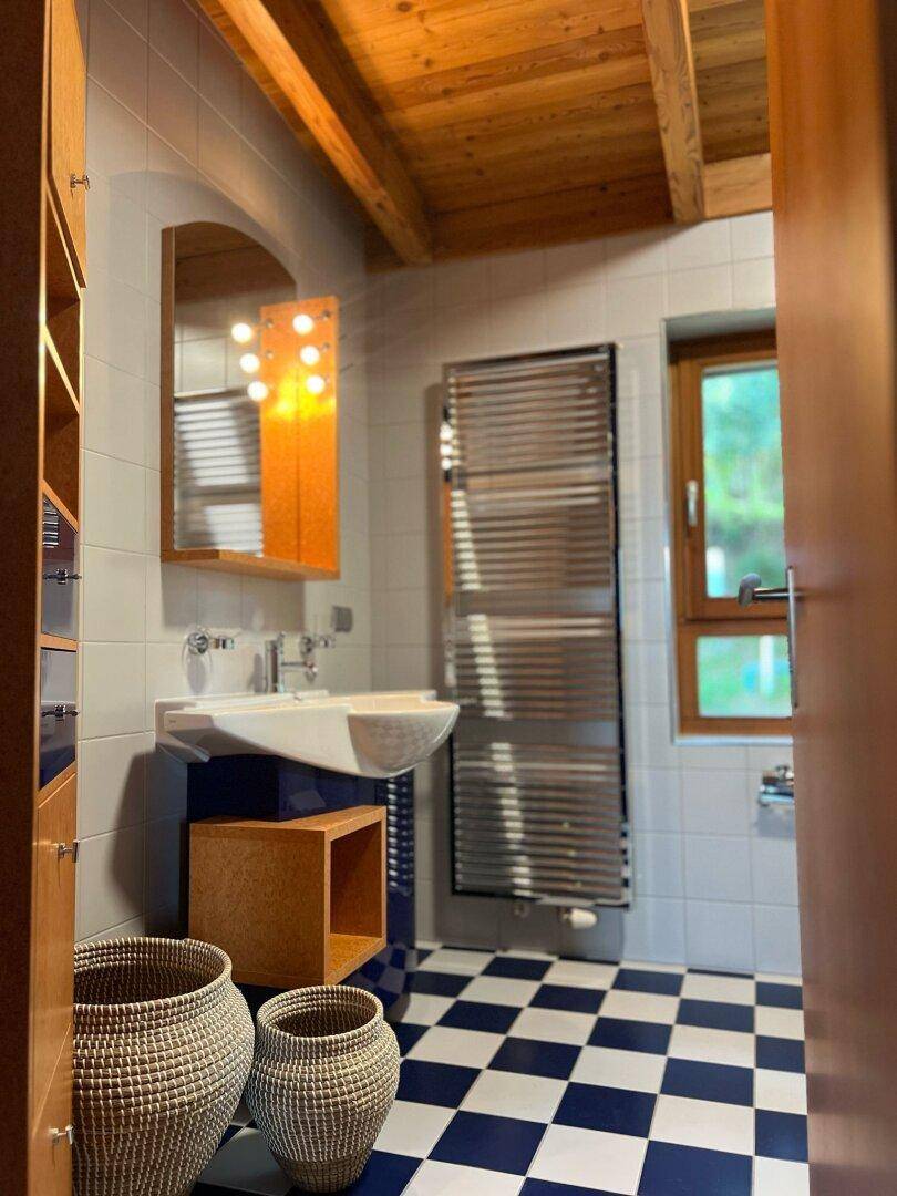Modernes Badezimmer mit blau-weiß karierten Fliesen, Holzdecke und beheiztem Handtuchhalter.
