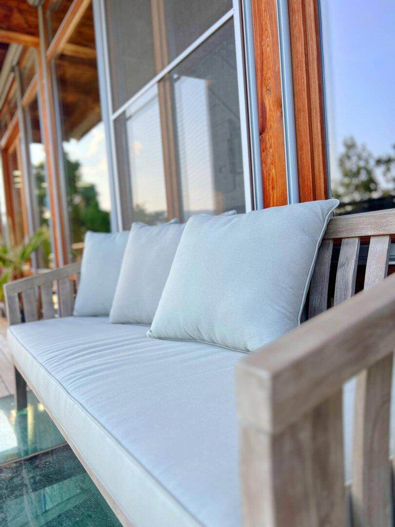 Gemütliche Sitzbank auf einem Balkon mit hellen Kissen und Blick auf die Umgebung.