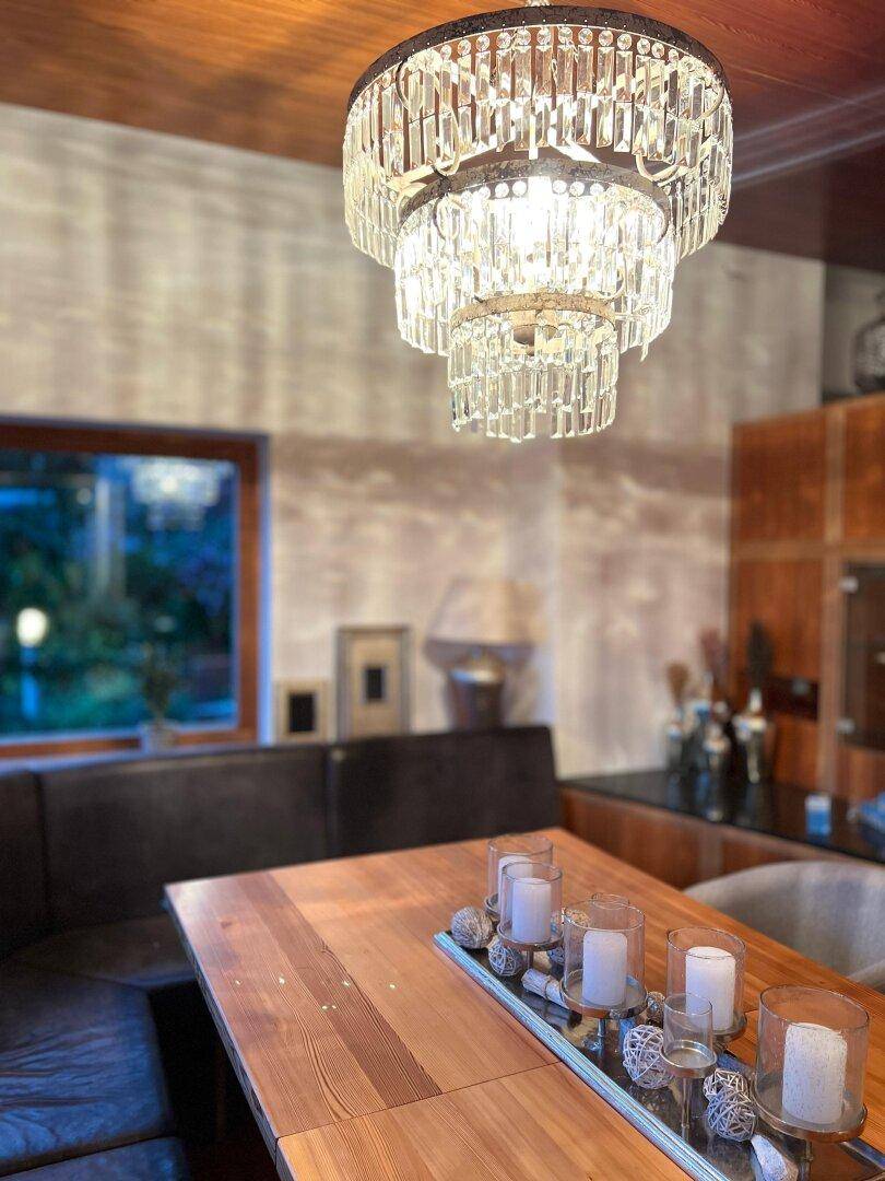 Eleganter Essbereich mit Holztisch, Kronleuchter und gemütlicher Sitzbank, ideal für gesellige Abende.
