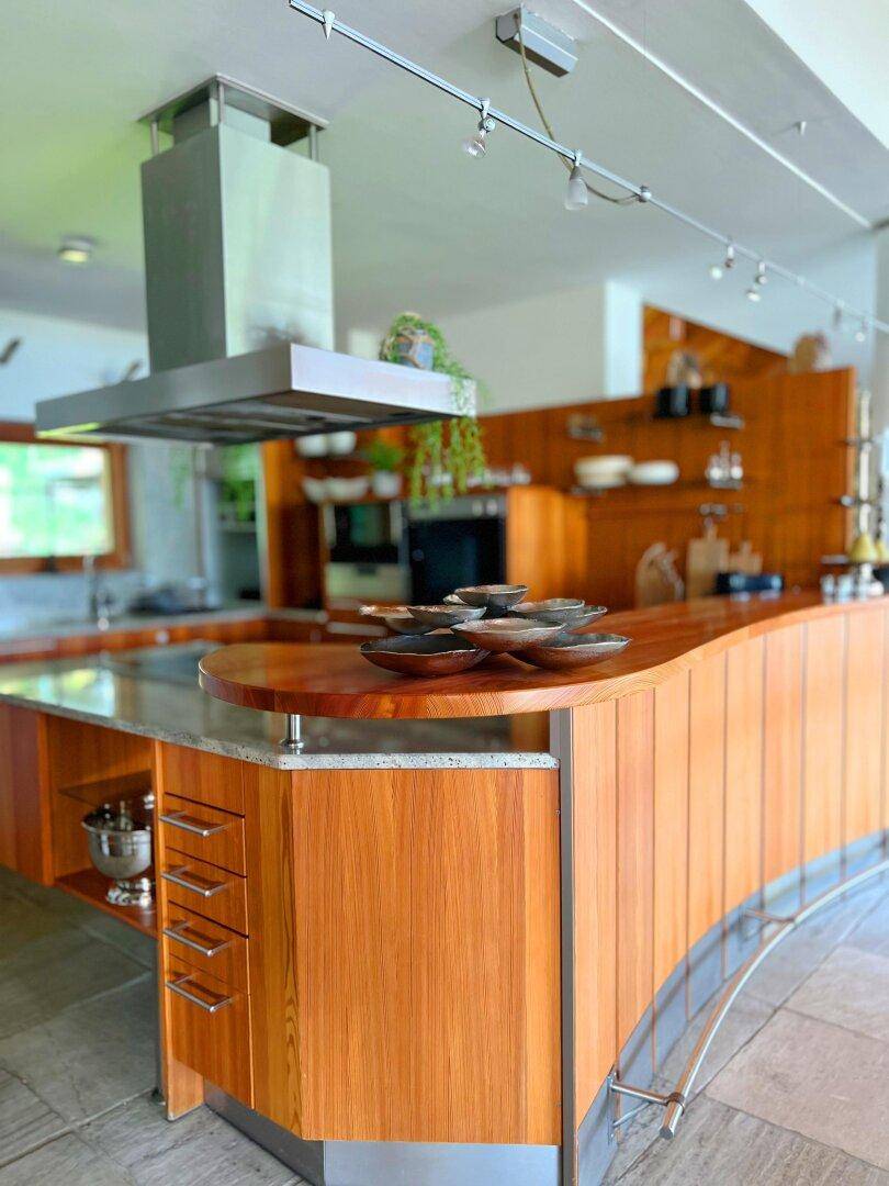Geräumige Küche mit Holzschränken, großer Kochinsel und moderner Dunstabzugshaube.