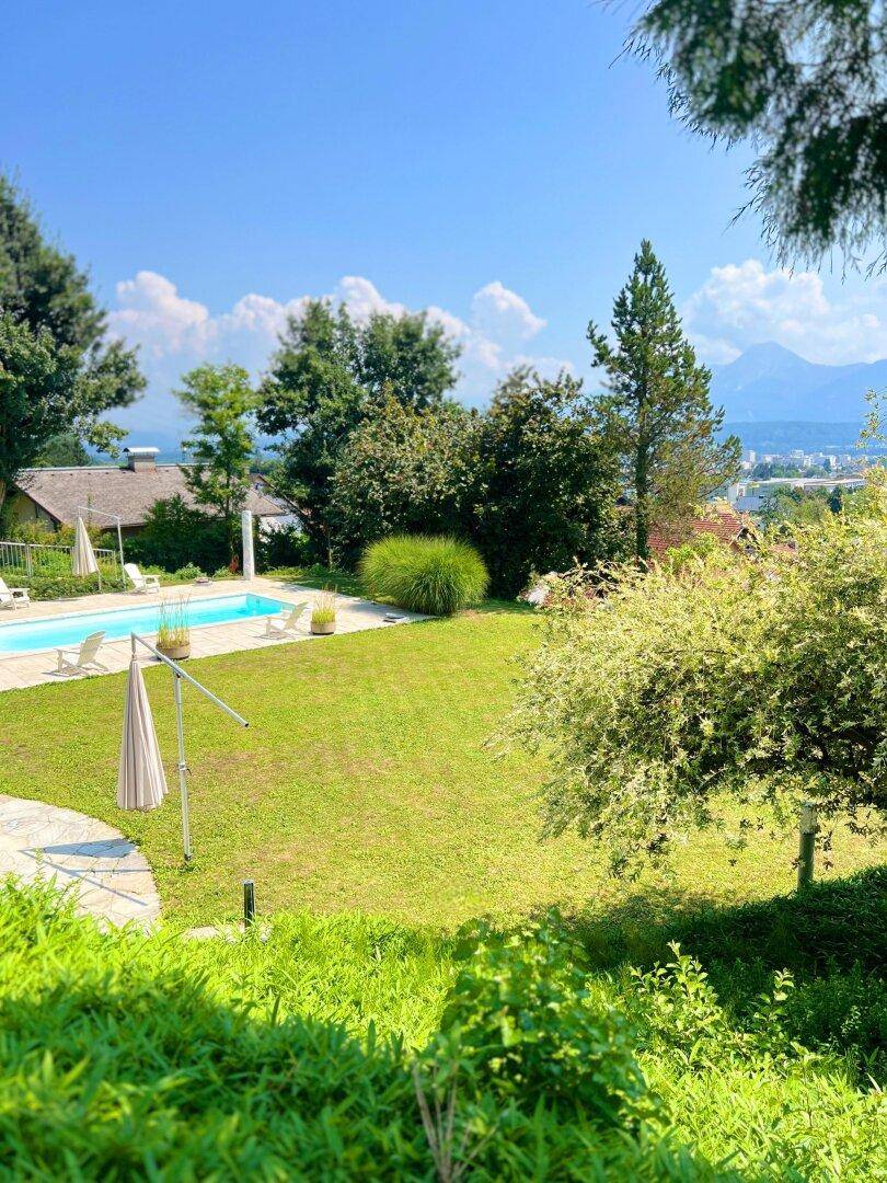 Weitläufiger Garten mit Swimmingpool, großer Rasenfläche und Fernblick auf die umliegende Landschaft.