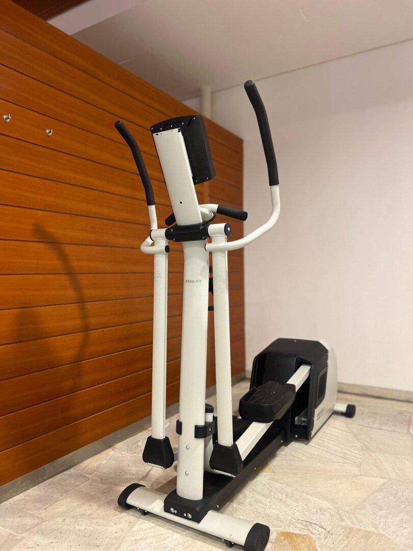 Heim-Fitnessraum mit Ellipsentrainer, Holzwandverkleidung und gefliestem Boden.