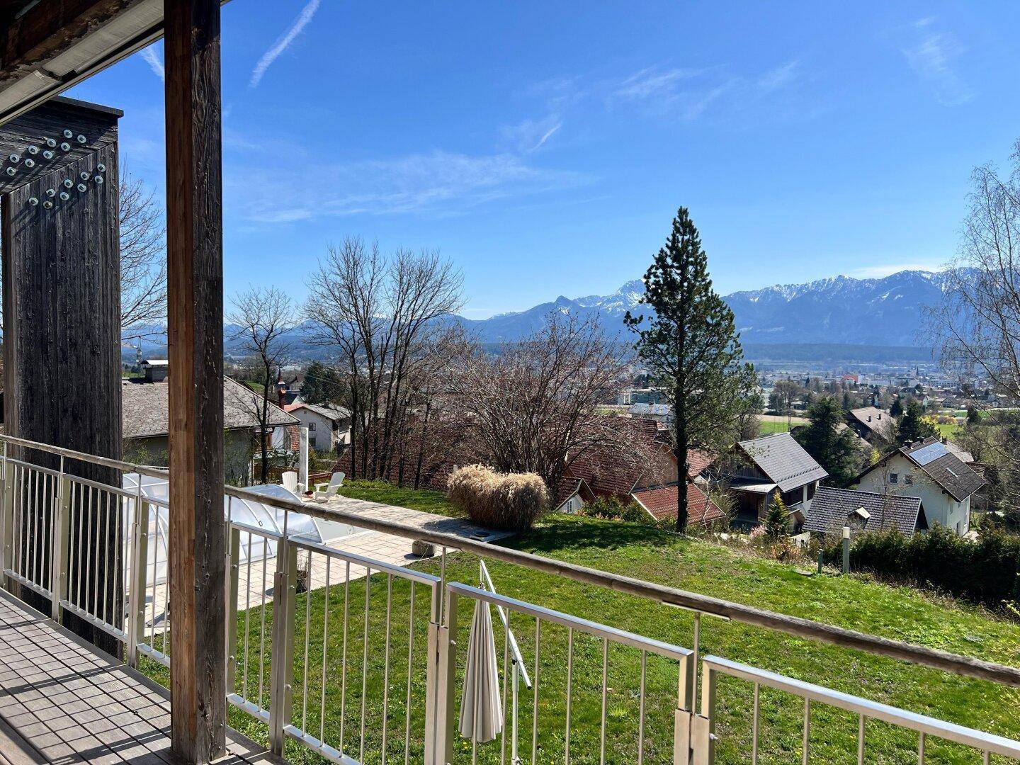 Geräumiger Balkon mit Holzboden und Metallgeländer, bietet weiten Blick auf Landschaft und Berge.