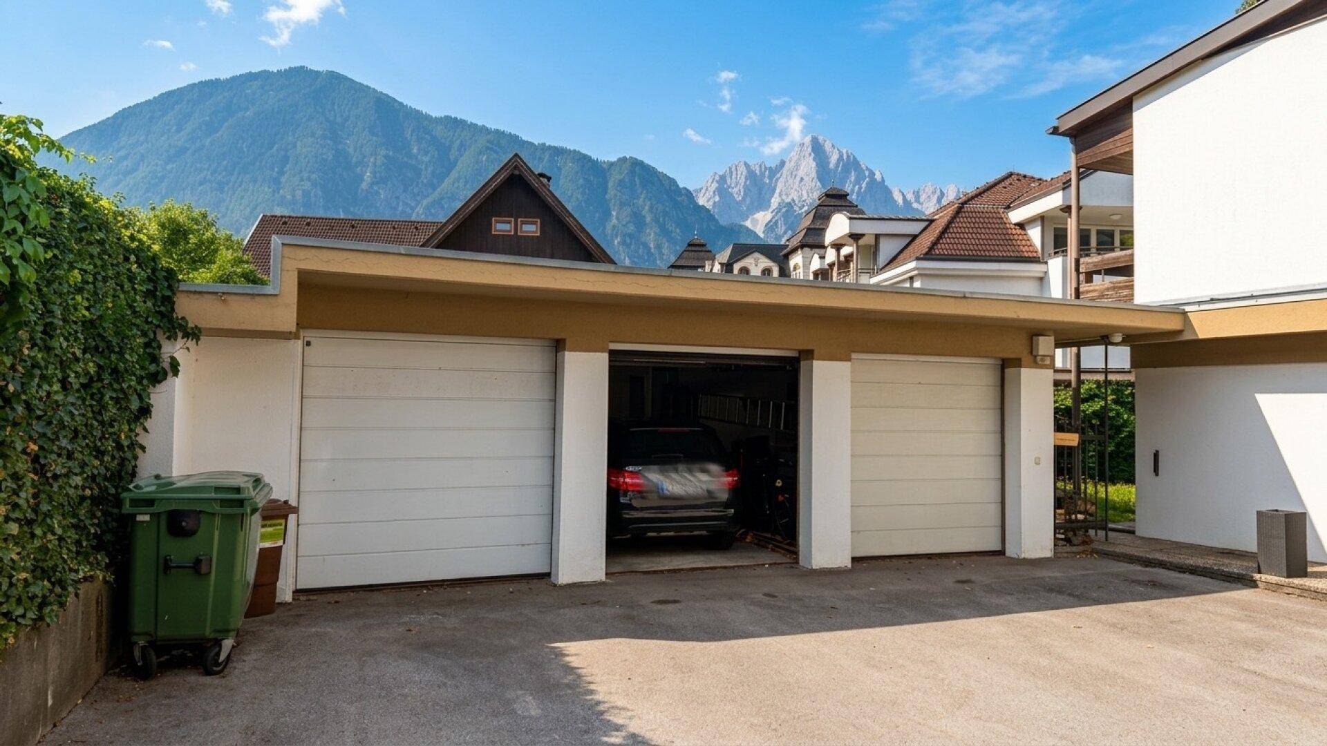 Doppelgarage mit einem geparkten Auto und einer beeindruckenden Berglandschaft im Hintergrund.
