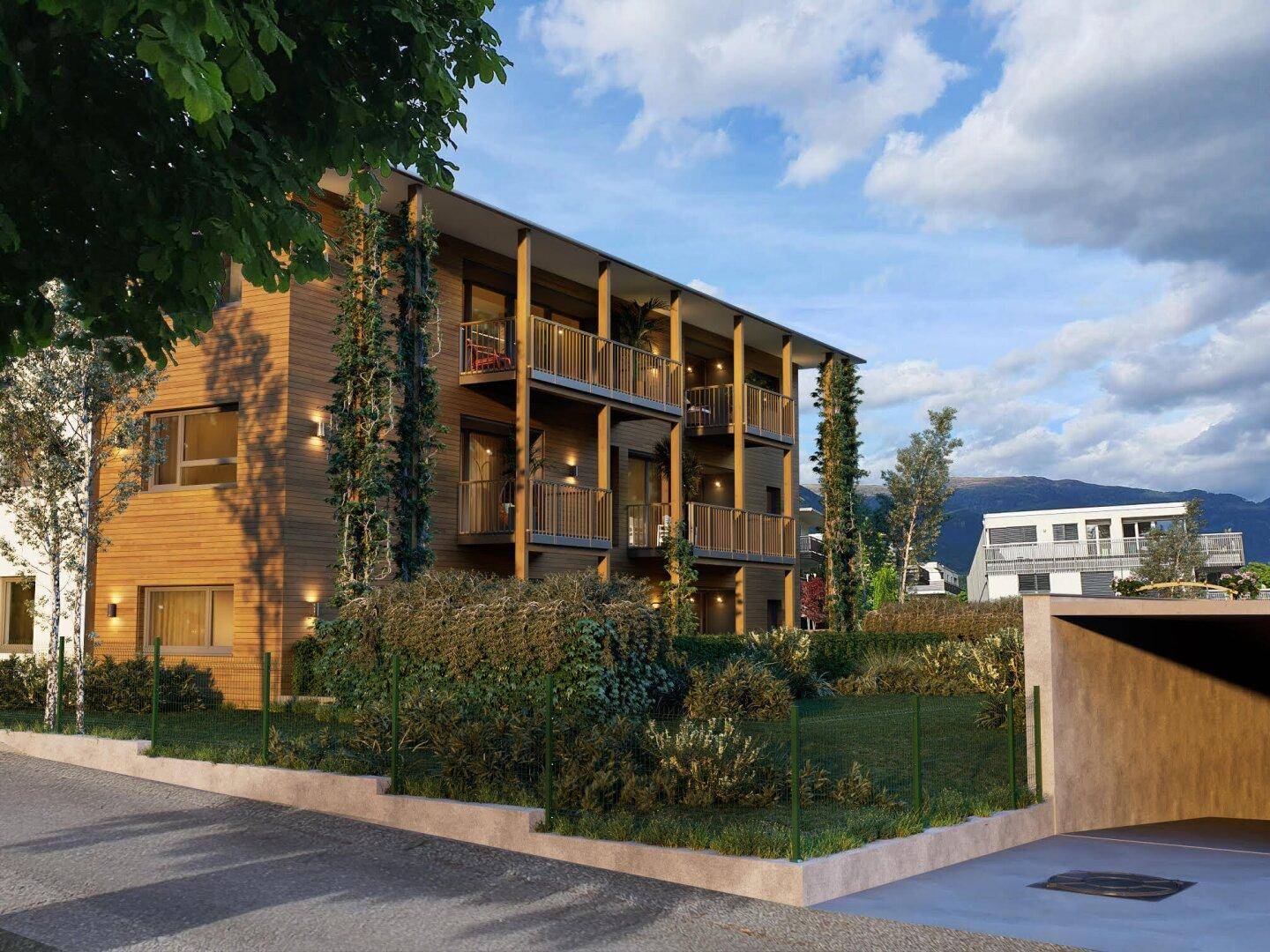 Modernes Apartmentgebäude mit Holzfassade und Balkonen, umgeben von Grünflächen und einem Carport-Bereich.