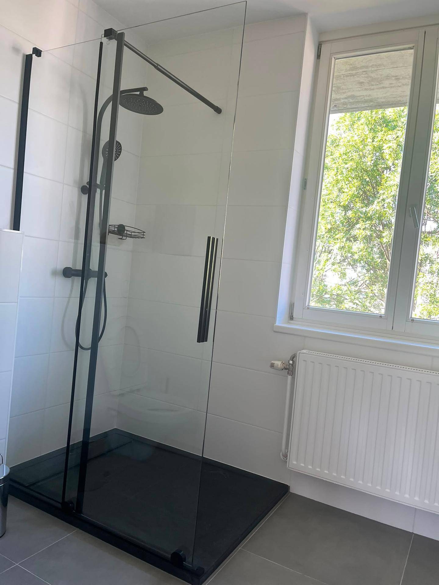 Modernes Badezimmer mit ebenerdiger Dusche, weißen Fliesen und Fenster.