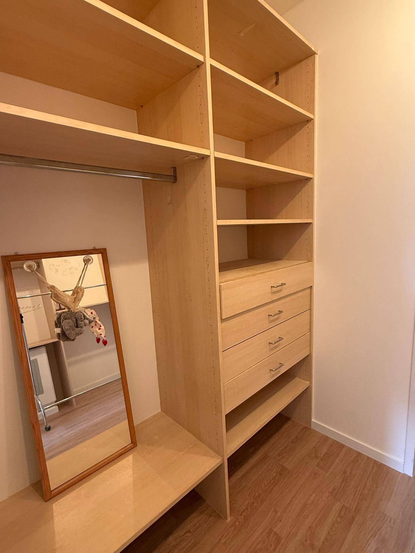Begehbarer Kleiderschrank mit offenen Regalen, Schubladen und einem Spiegel.