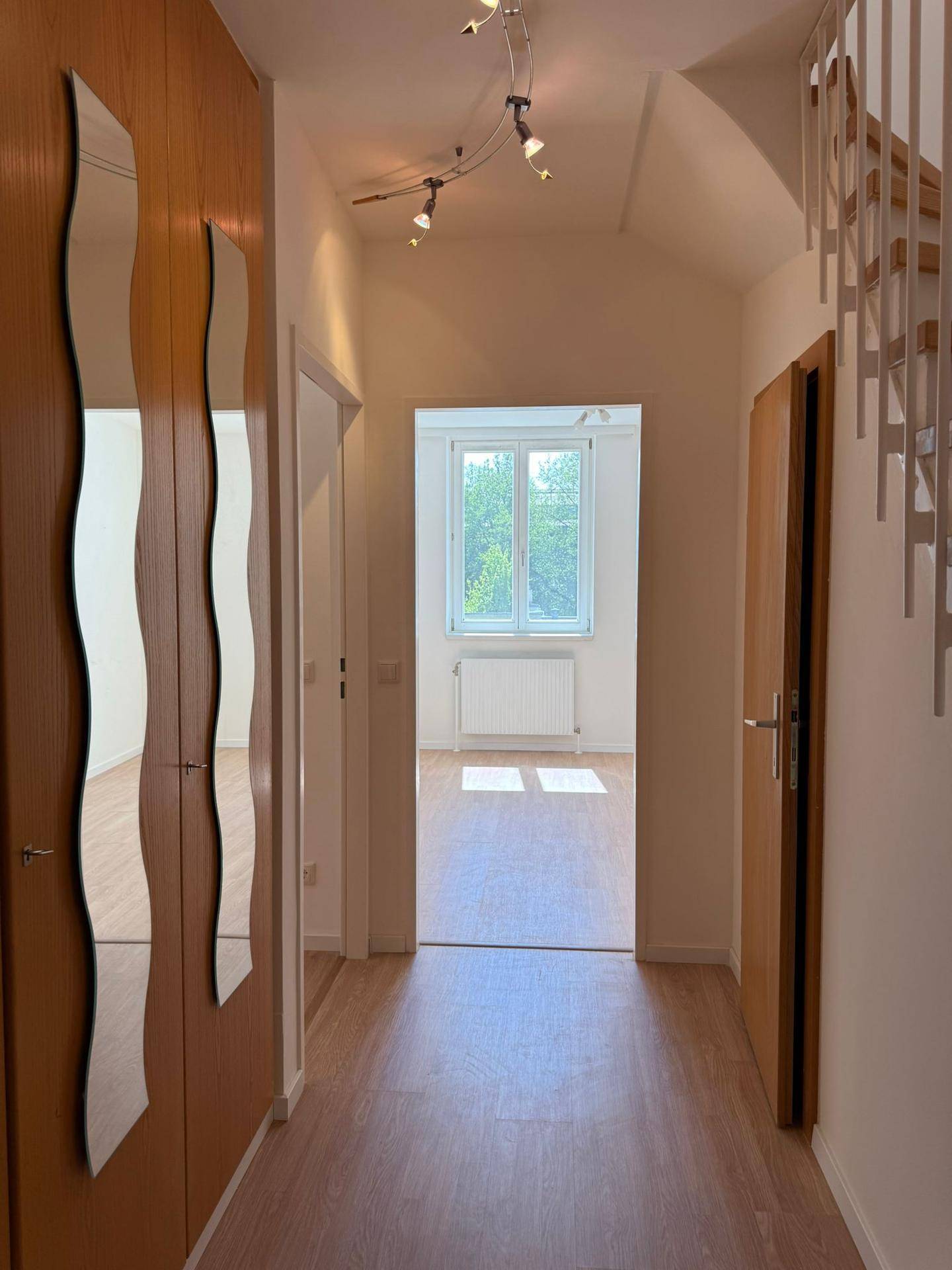 Heller Flur mit Laminatboden, Spiegeln und Zugang zu weiteren Räumen.