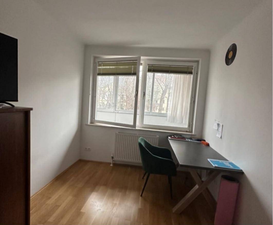 Helles Zimmer mit Schreibtisch, Fenster und Heizkörper, ideal als Büro oder Gästezimmer nutzbar.