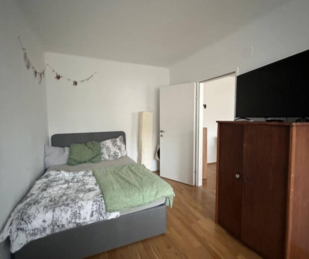 Gemütliches Schlafzimmer mit Bett, Holzschrank und Fernseher, bietet eine ruhige Rückzugsmöglichkeit.
