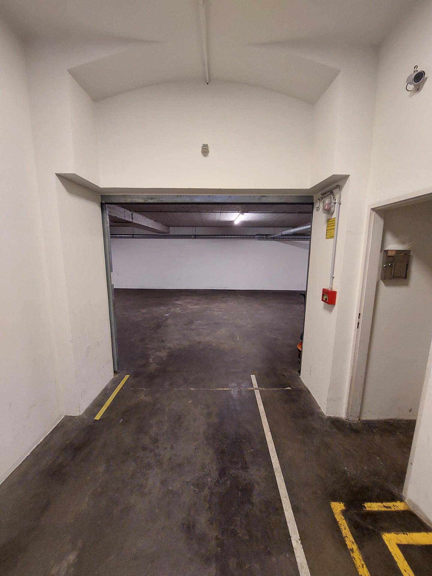 Einfahrt zu einer Tiefgarage mit Betonboden und gelben sowie weißen Markierungen.