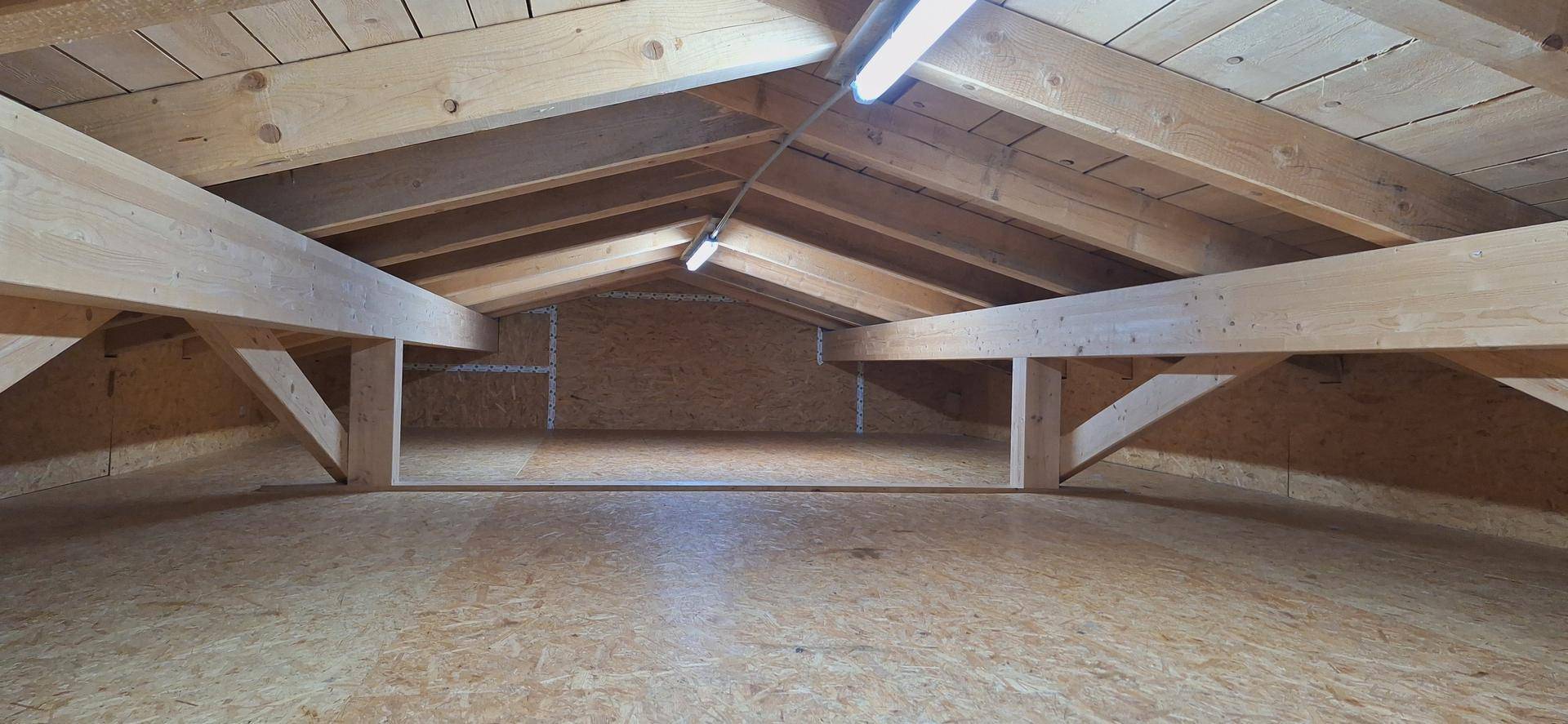 Geräumiger Dachboden mit sichtbaren Holzbalken und Holzfußboden, ideal als Stauraum.