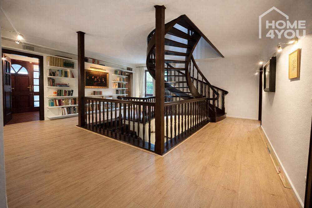 Geräumiger Flur mit Wendeltreppe, integrierten Bücherregalen und hellem Holzboden.