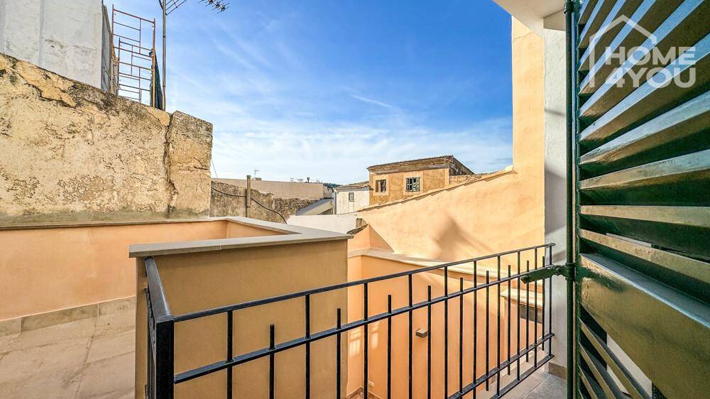 Kleiner Balkon mit schmiedeeisernem Geländer und Blick auf die umliegenden Gebäude.