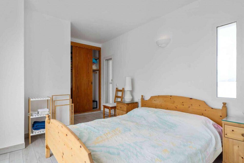 Geräumiges Schlafzimmer mit Doppelbett aus Holz, Nachttischen und integriertem Kleiderschrank.