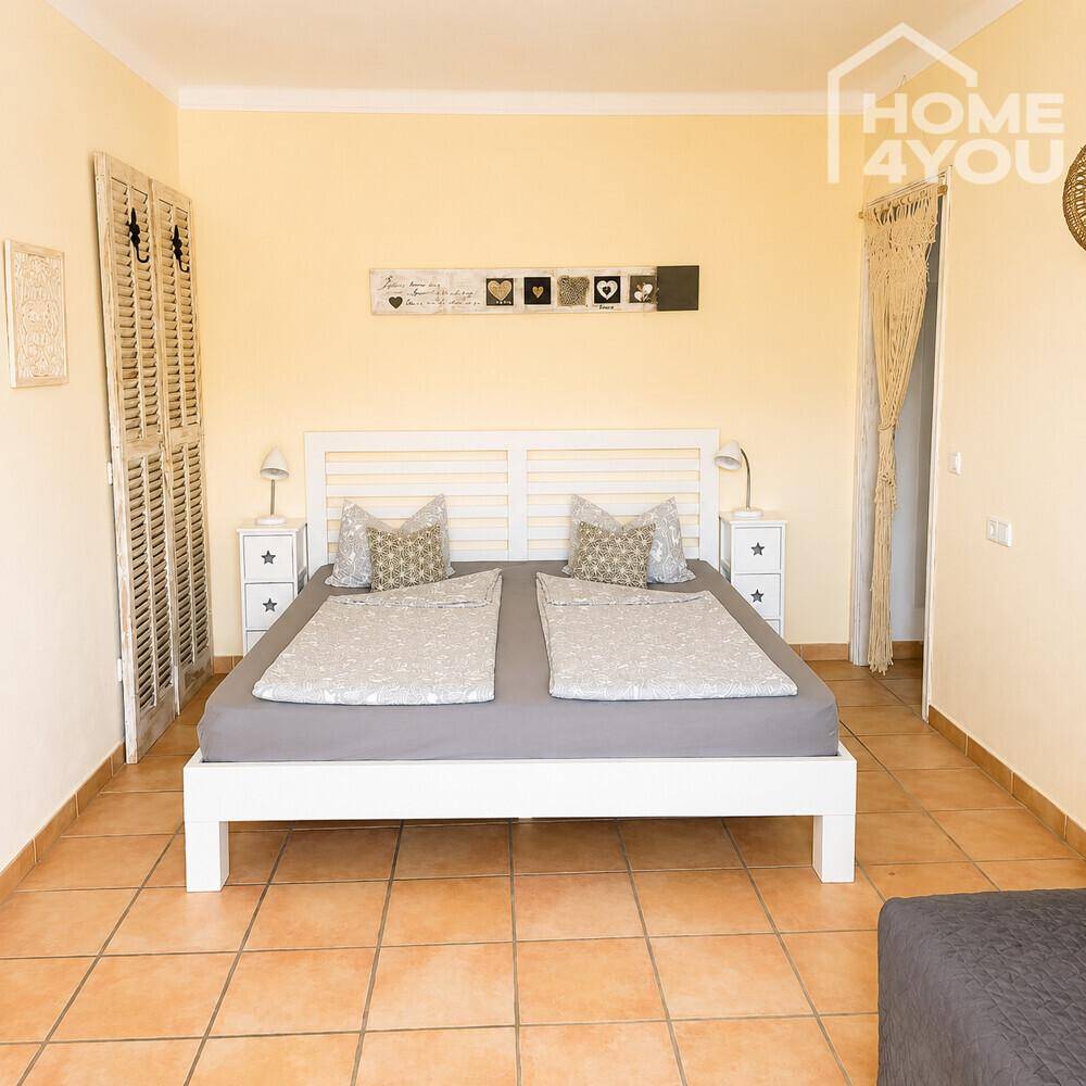 Gemütliches Schlafzimmer mit hellem Bett, Nachttischen und traditionellem Fliesenboden.