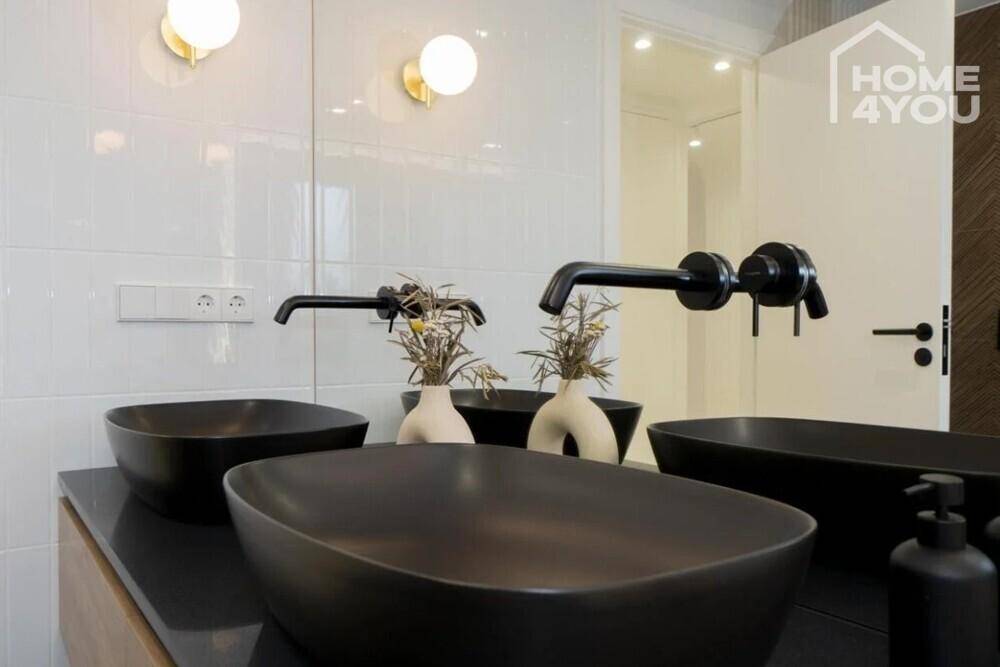 Luxuriöses Badezimmer mit zwei schwarzen Aufsatzwaschbecken und modernen Armaturen.