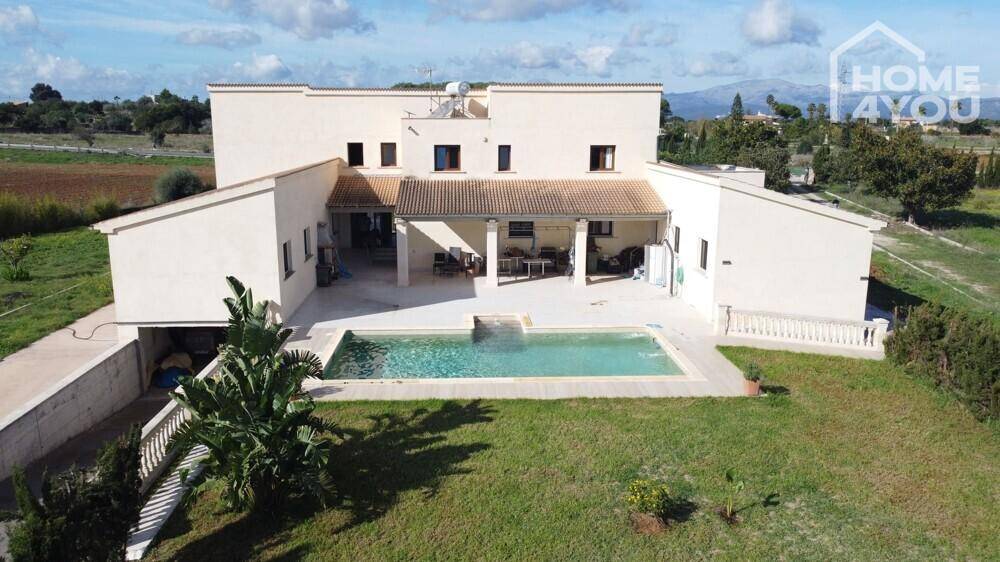 Ansicht des Hauses von hinten mit großem Poolbereich und überdachter Terrasse.