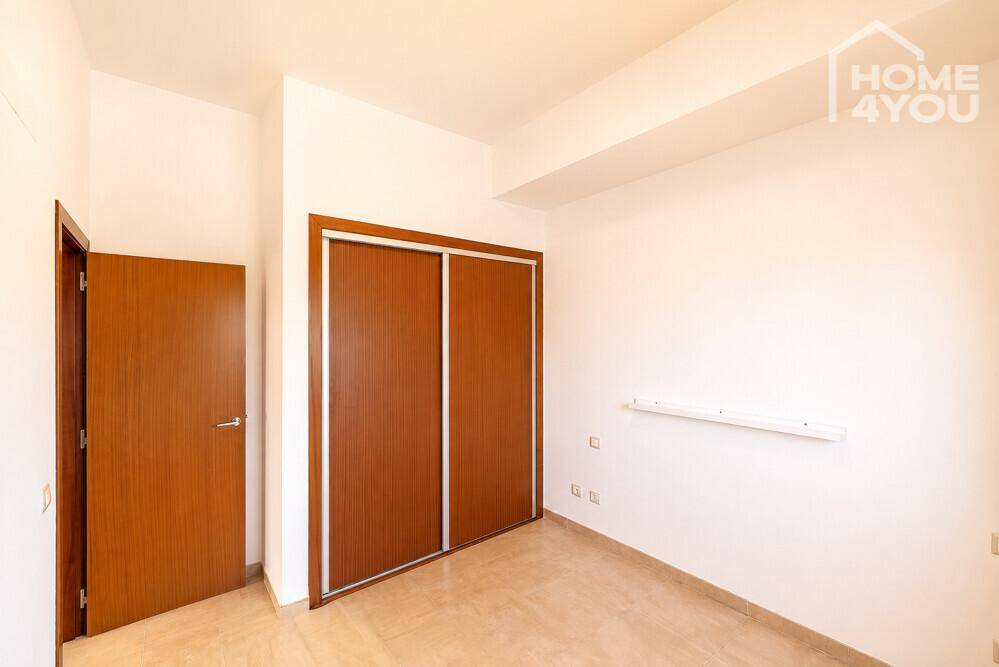 Schlafzimmer mit Fliesenboden, Einbauschrank und Holztür, bereit zur individuellen Gestaltung.