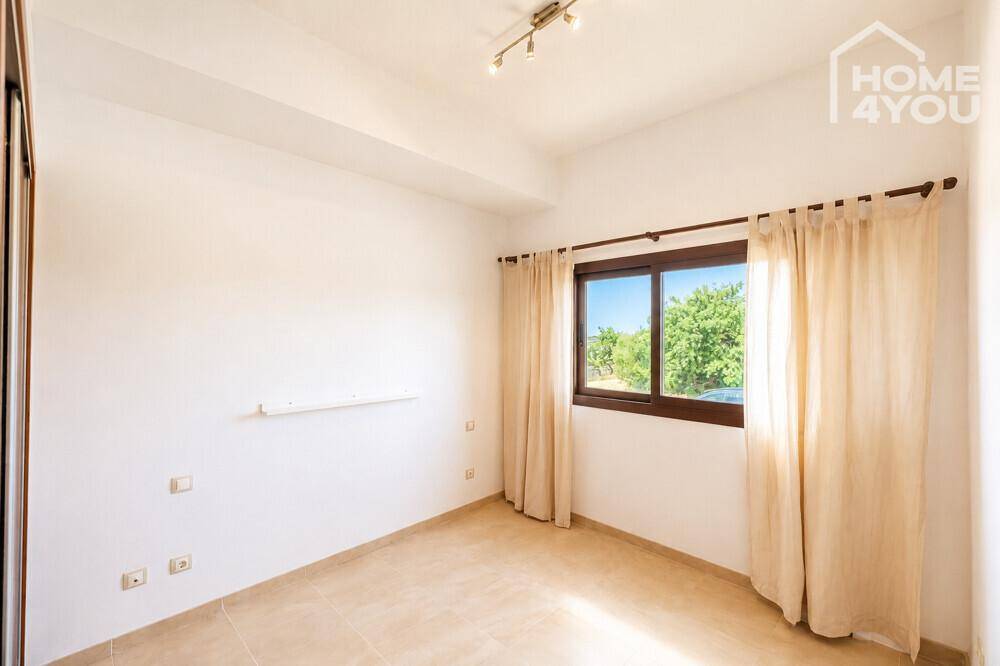 Helles Schlafzimmer mit Fliesenboden, Fenster und Vorhängen, bereit zur Einrichtung.