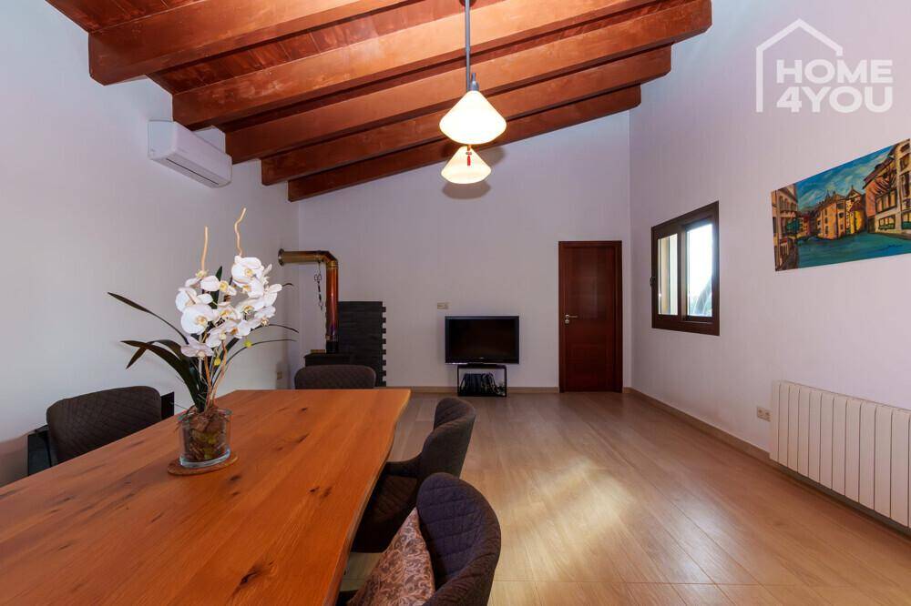 Essbereich mit rustikalem Holztisch und sichtbaren Holzbalken an der Decke, die Gemütlichkeit verleihen.