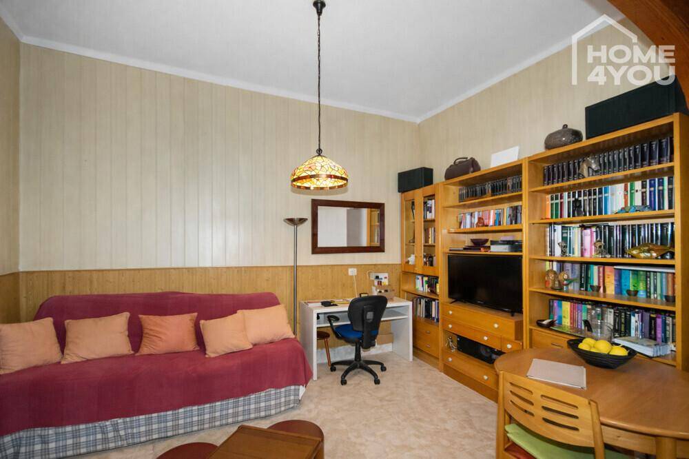 Wohnzimmer mit Sofa, Bücherregalen und einem Schreibtisch, ideal für Arbeit und Entspannung.