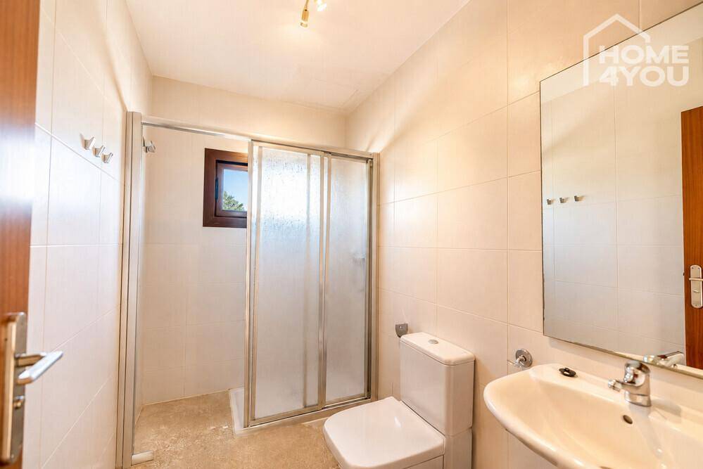 Badezimmer mit Duschkabine, WC, Waschbecken und Fenster für natürliche Belüftung.