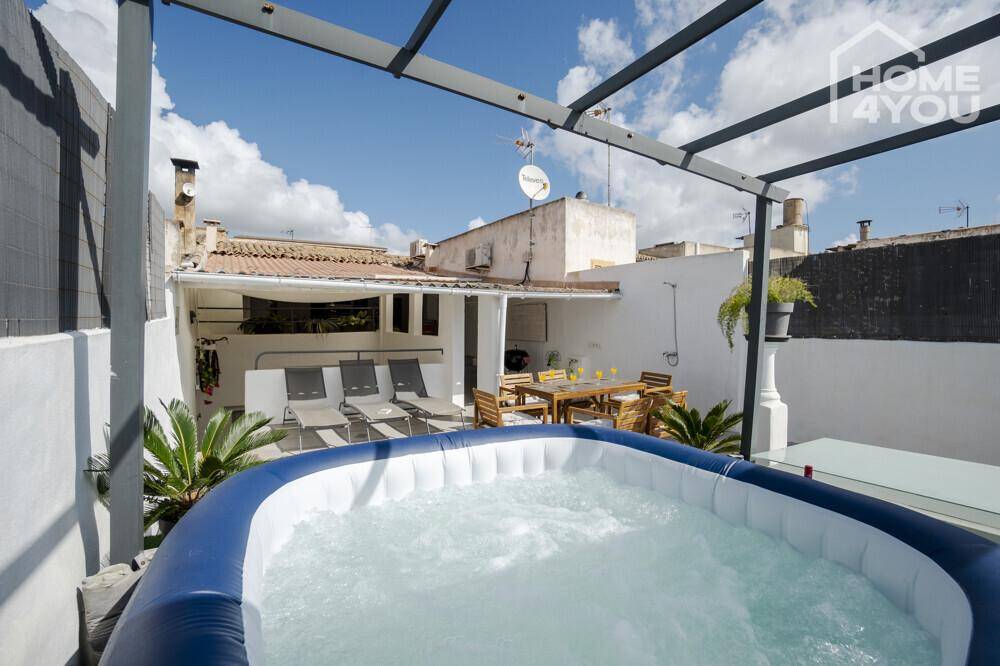 Dachterrasse mit Whirlpool und Liegestühlen, bietet einen entspannten Bereich unter blauem Himmel.