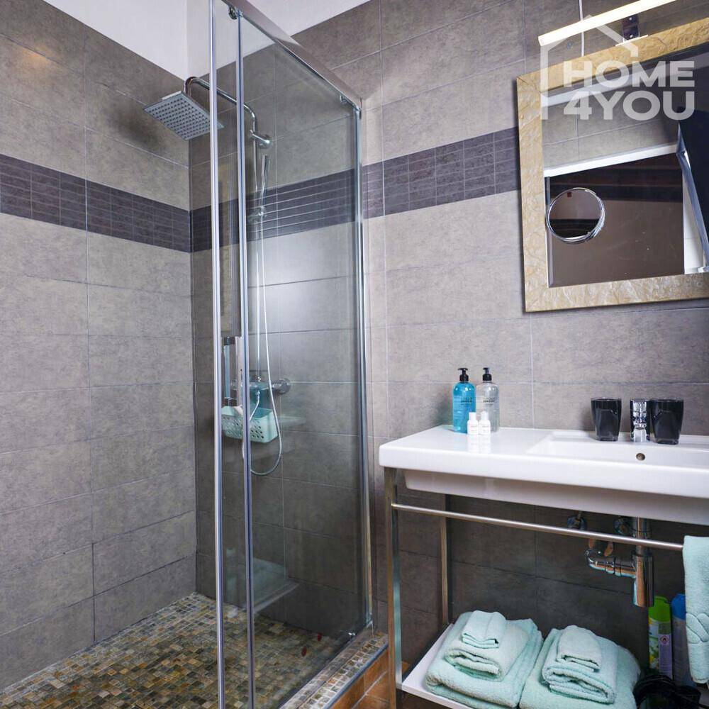 Modernes Badezimmer mit begehbarer Dusche, Waschtisch und grauen Wandfliesen.