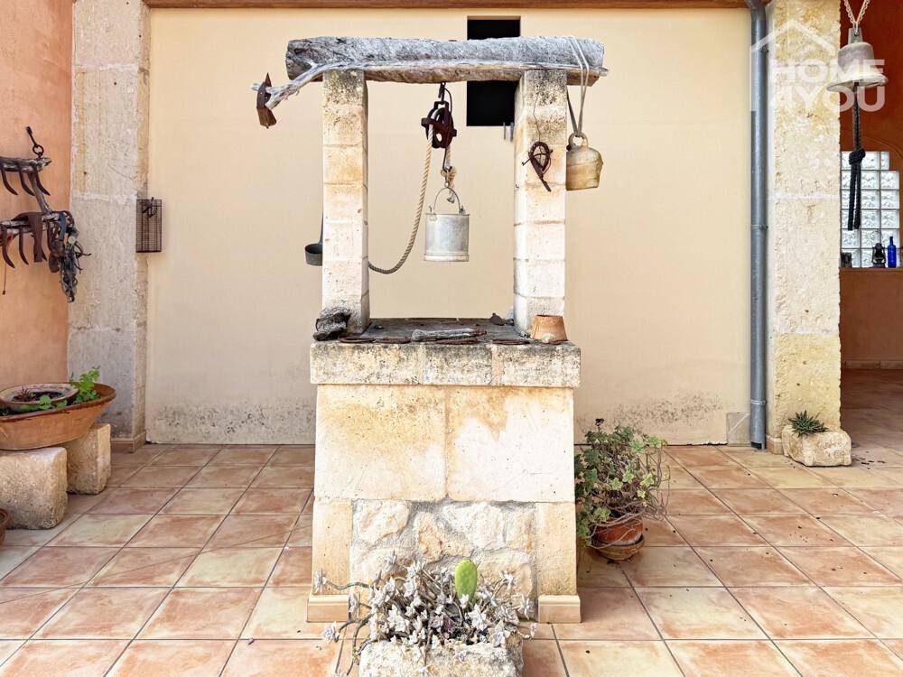 Innenhof mit einem traditionellen Steinbrunnen und Terrakotta-Fliesenboden.