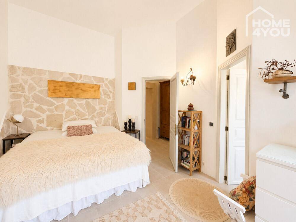 Geräumiges Schlafzimmer mit Steinwand, Holzboden und dekorativen Elementen.