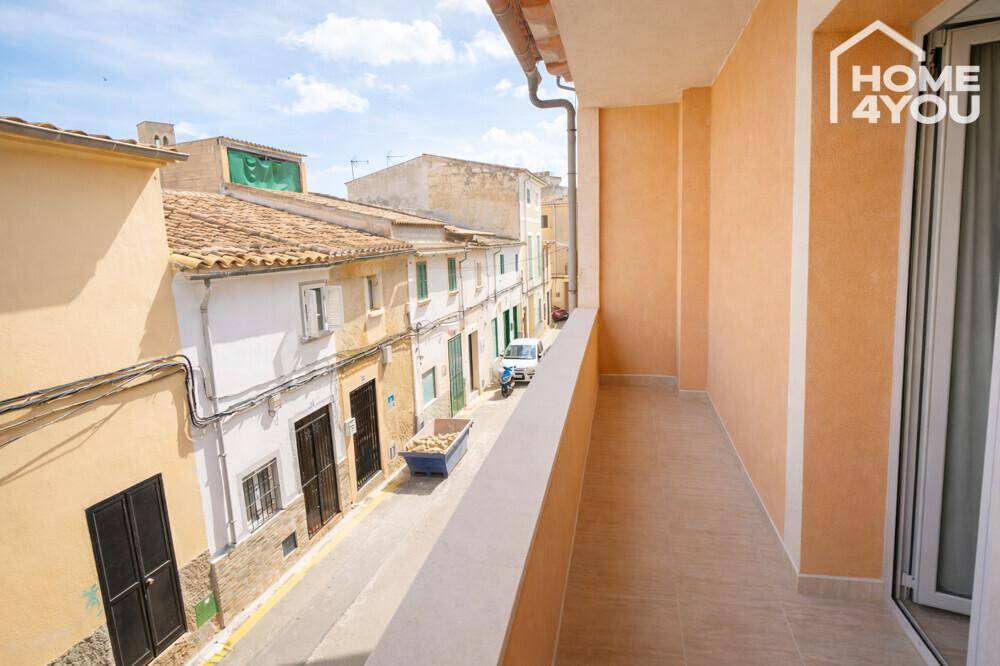 Langer Balkon mit Fliesenboden und Blick auf eine charmante, traditionelle Straße.