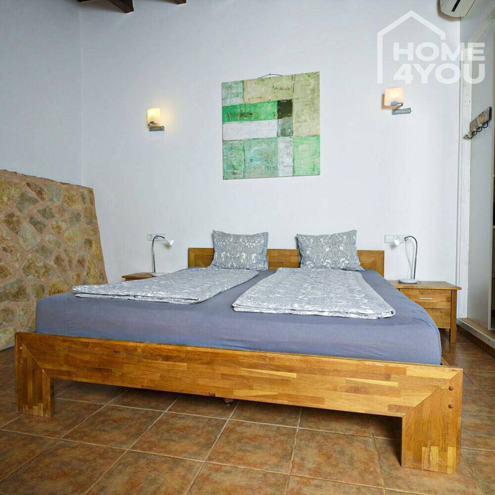 Geräumiges Schlafzimmer mit Holzbett, Kunstwerk und traditionellem Fliesenboden.