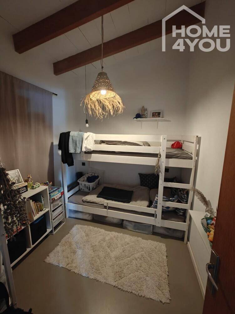 Kinderzimmer mit Etagenbett, Teppich und Holzbalken an der Decke.