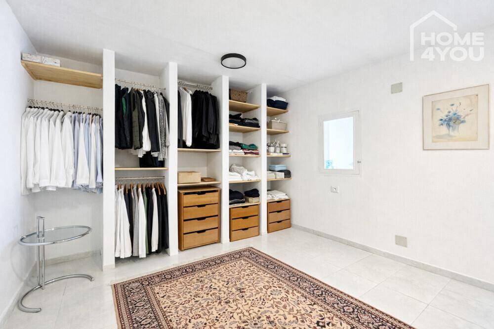 Geräumiger begehbarer Kleiderschrank mit offenen Regalen und Kleiderstangen für viel Stauraum.