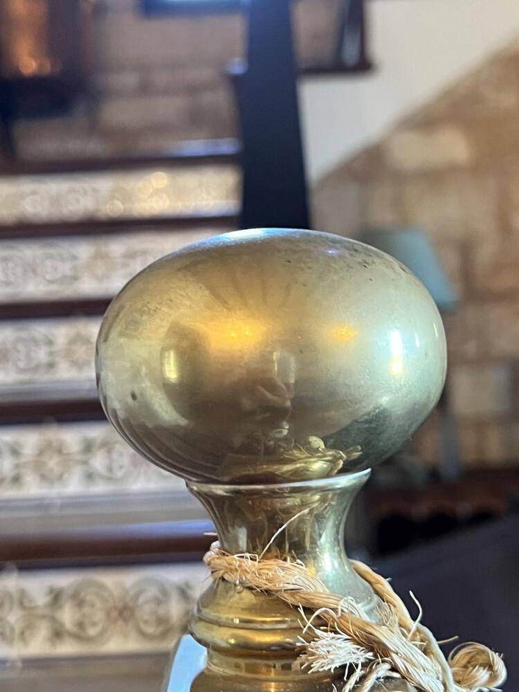 Detailaufnahme eines glänzenden Messingknaufs am Treppengeländer, der Eleganz verleiht.