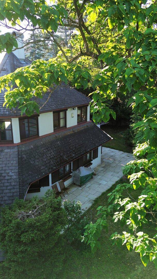 Ansicht des Hauses von oben, umgeben von üppigem Grün und Bäumen.