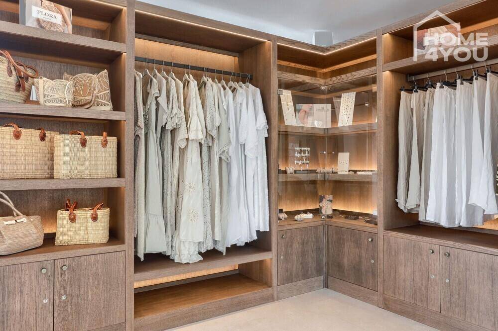 Geräumiger begehbarer Kleiderschrank mit Holzregalen und integrierter Beleuchtung.