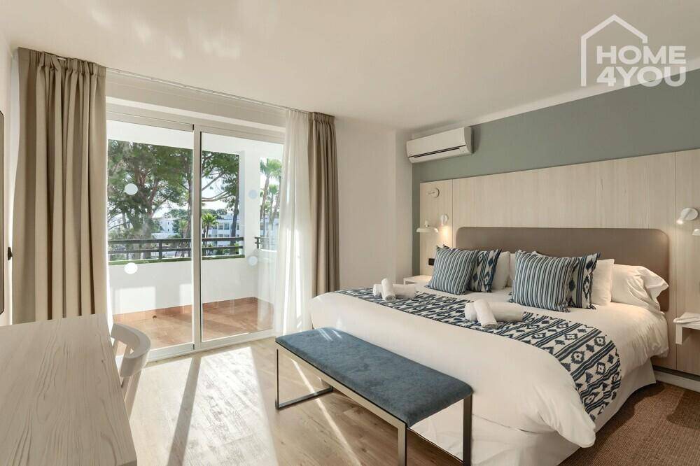 Helles Schlafzimmer mit Doppelbett, Klimaanlage und direktem Zugang zu einem sonnigen Balkon.