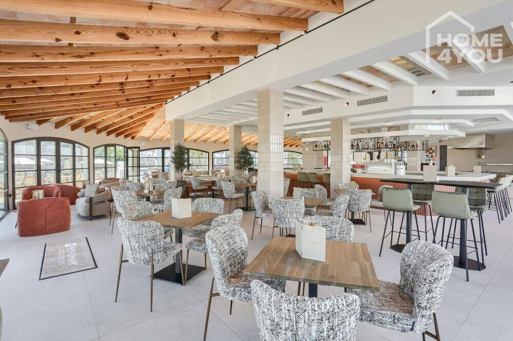 Großer Speisesaal mit vielen Tischen, Stühlen und sichtbaren Holzdeckenbalken.
