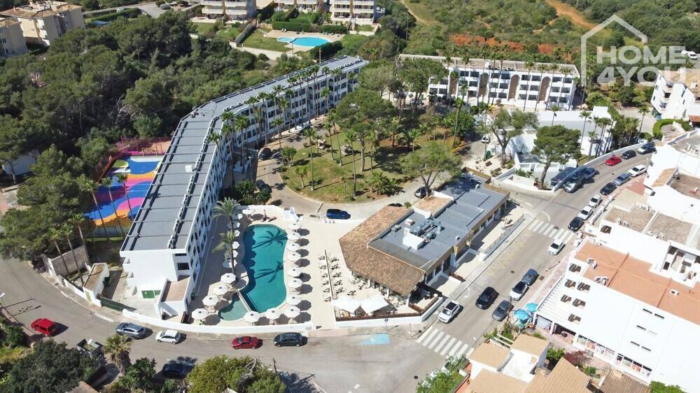 Luftaufnahme eines weitläufigen Resort-Komplexes mit mehreren Gebäuden, Pools und Parkplätzen.