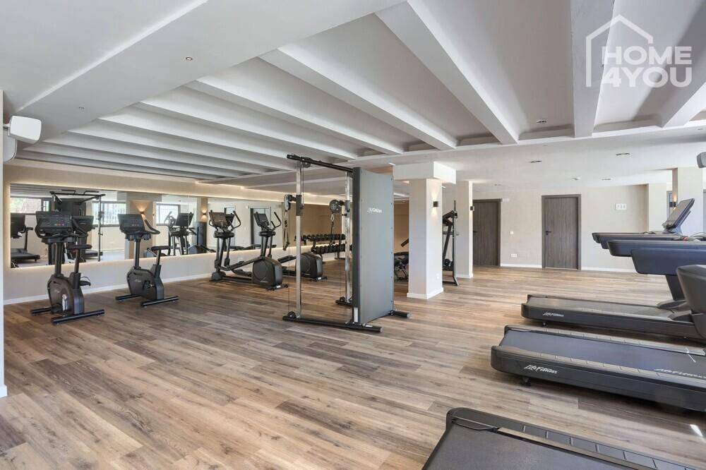 Geräumiges Fitnessstudio mit Laufbändern, Fahrrädern und Spiegelfronten für das Training.