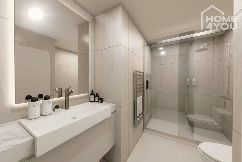Modernes Badezimmer mit begehbarer Dusche, Einzelwaschbecken und beleuchtetem Spiegel.