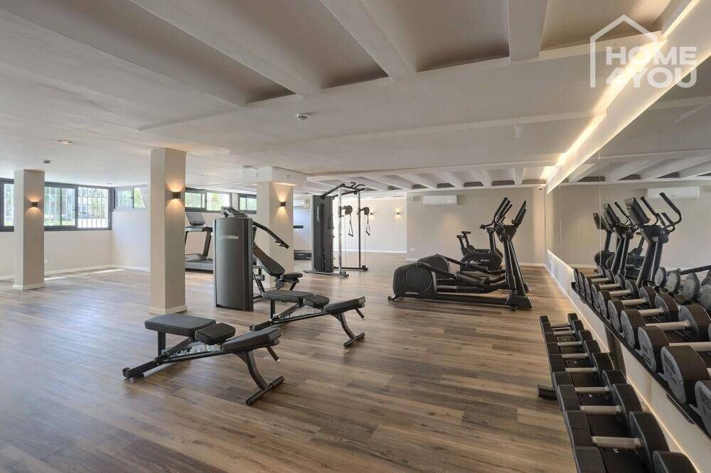 Modernes Fitnessstudio mit einer Vielzahl von Trainingsgeräten und Hanteln.