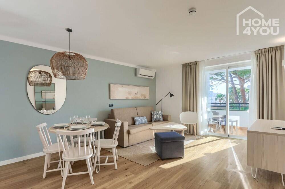 Gemütlicher Wohn- und Essbereich mit Holzboden, Esstisch und Zugang zu einem Balkon.