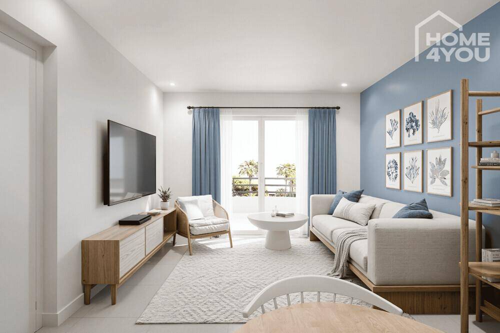 Helles Wohnzimmer mit blauer Akzentwand, modernem Sofa und Fernseher an der Wand.