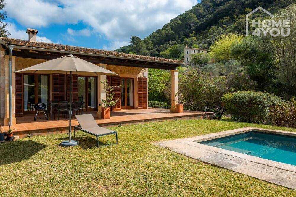 Mediterranes Haus mit Pool und Garten, eingebettet in eine hügelige, grüne Landschaft.