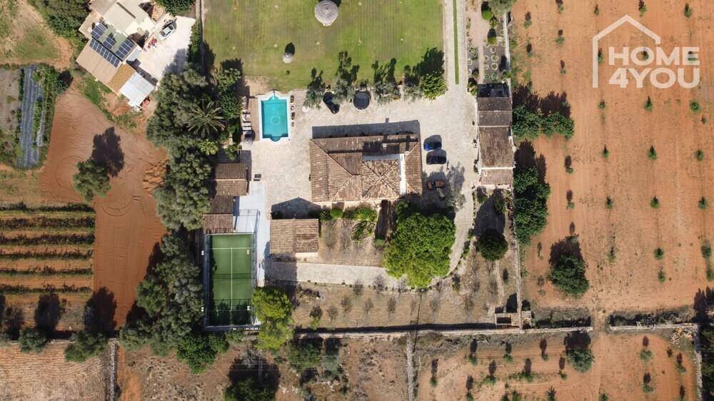 Weitläufiges Anwesen mit mehreren Gebäuden, Pool, Tennisplatz und umgebenden Feldern.