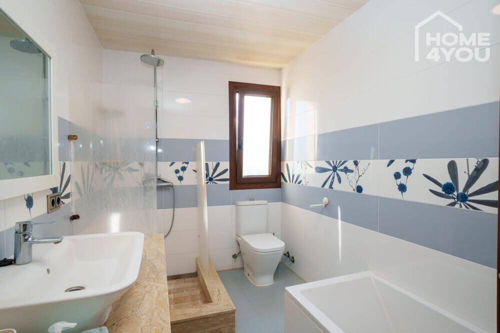Farbig gefliestes Badezimmer mit Badewanne, Dusche, WC und Waschbecken, hell und funktional.